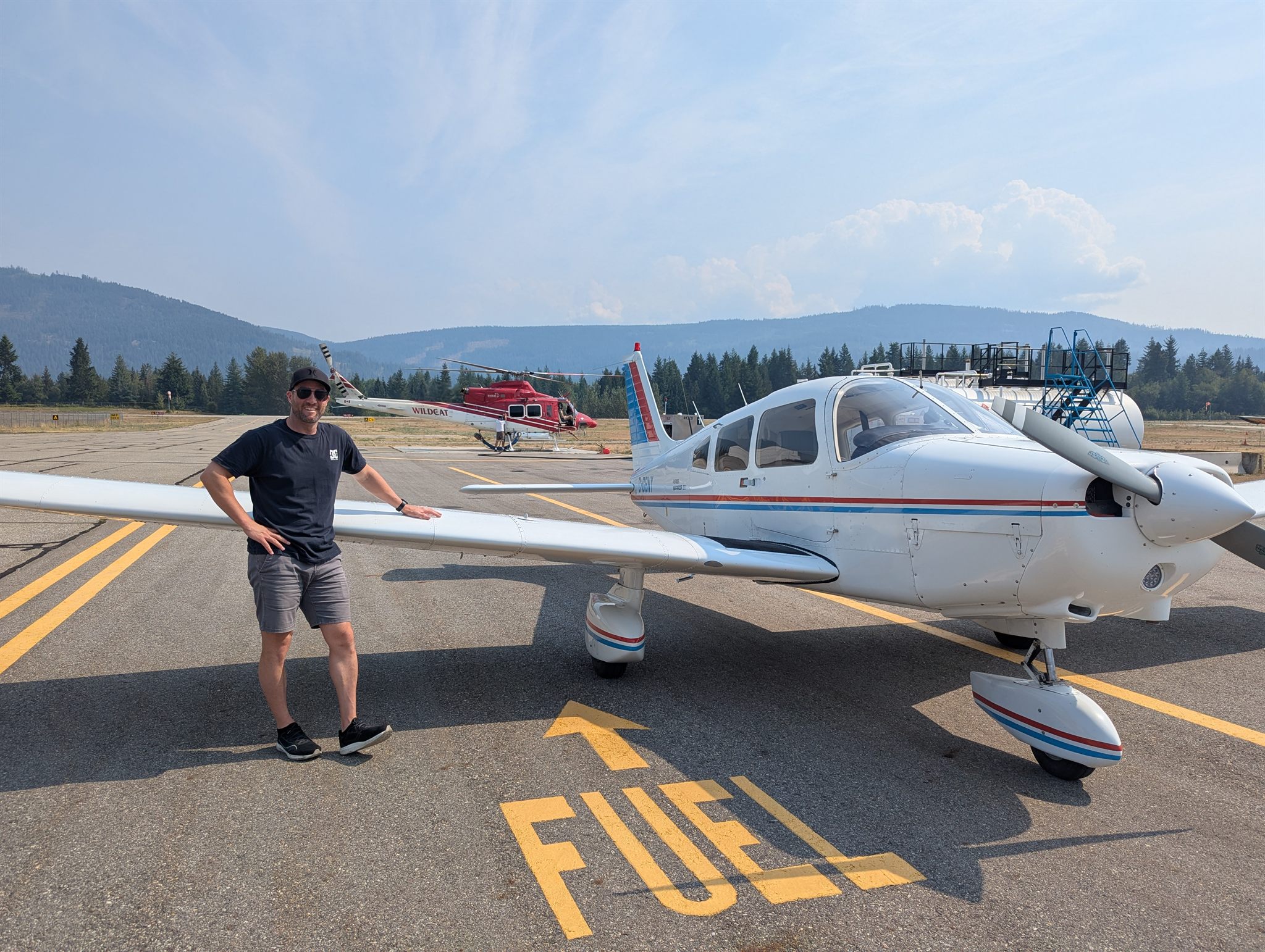 The club's white Piper Warrior II, C-GBNY, parked beside the fuel pad at Salmon Arm airport, with a pilot standing by its wing